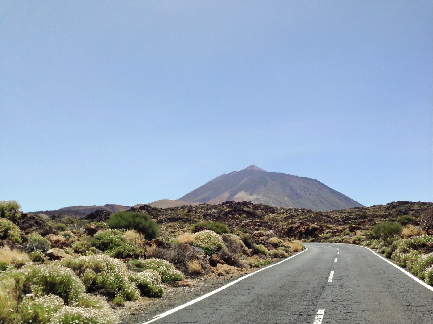 An empty road curving through volcanic scrubland towards Mount Teide on Tenerife